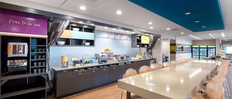 A modern kitchen area with a long counter, bar stools, and a sign that reads "inspired table".