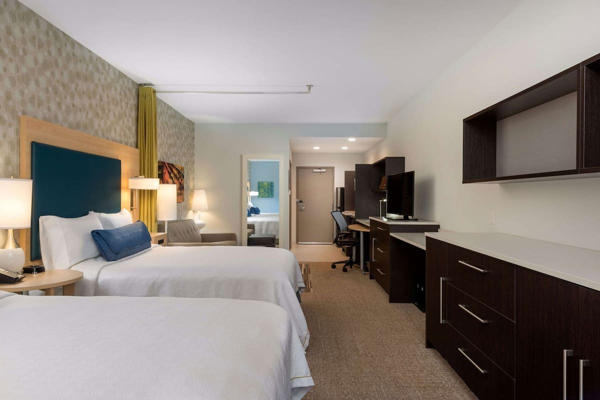 Une chambre d’hôtel avec deux lits, un bureau, une télévision et une armoire.
