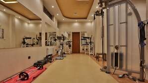 A gym with weightlifting equipment, mirrors, and exercise machines. - Marina Residence Boutique hotel (Varna)
