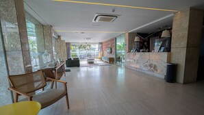 Um hall amplo com balcão de atendimento, área de estar e grandes janelas com vista para o exterior.