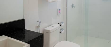 A modern bathroom with a white toilet, a black countertop, a glass shower enclosure, and a visible towel rack.