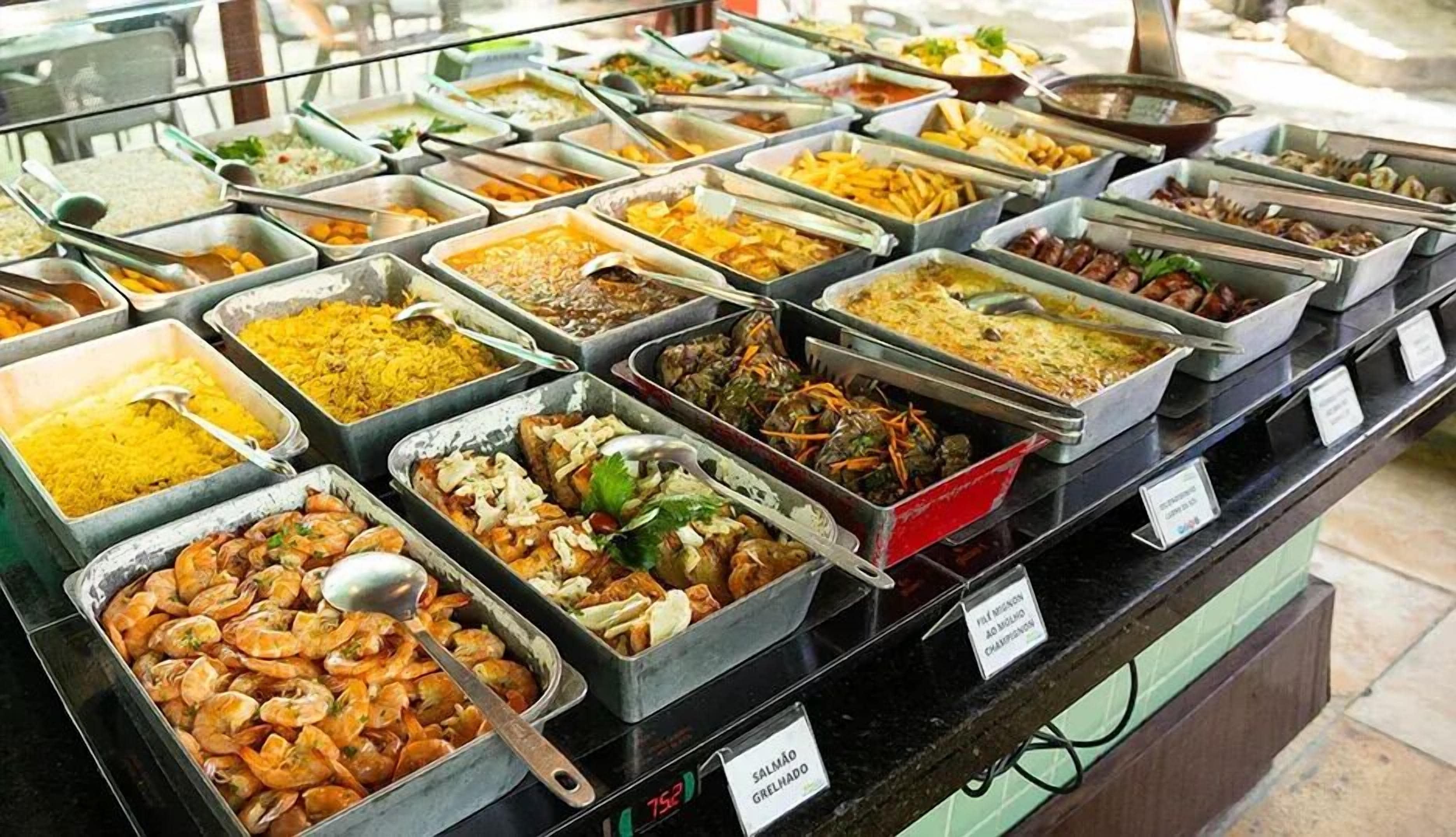 Un bufé con diversos platos, entre ellos camarones, arroz y ensaladas.