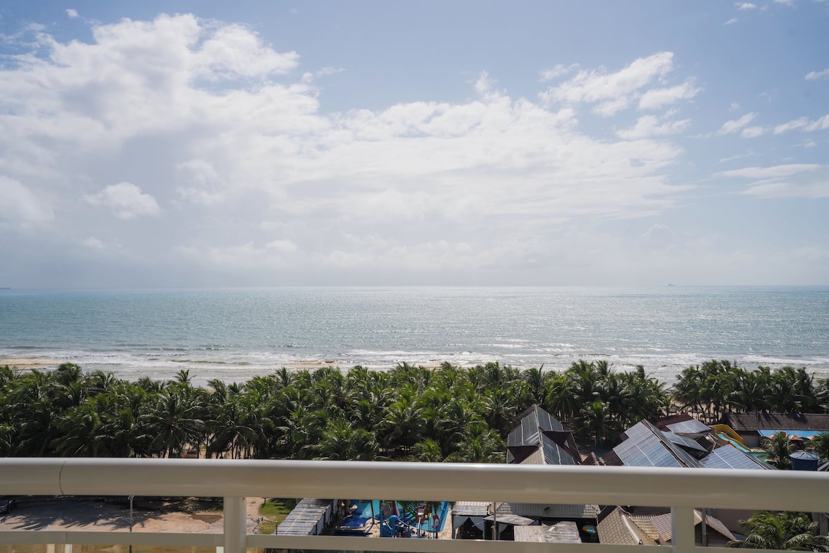 A beach view with palm trees and a clear sky.