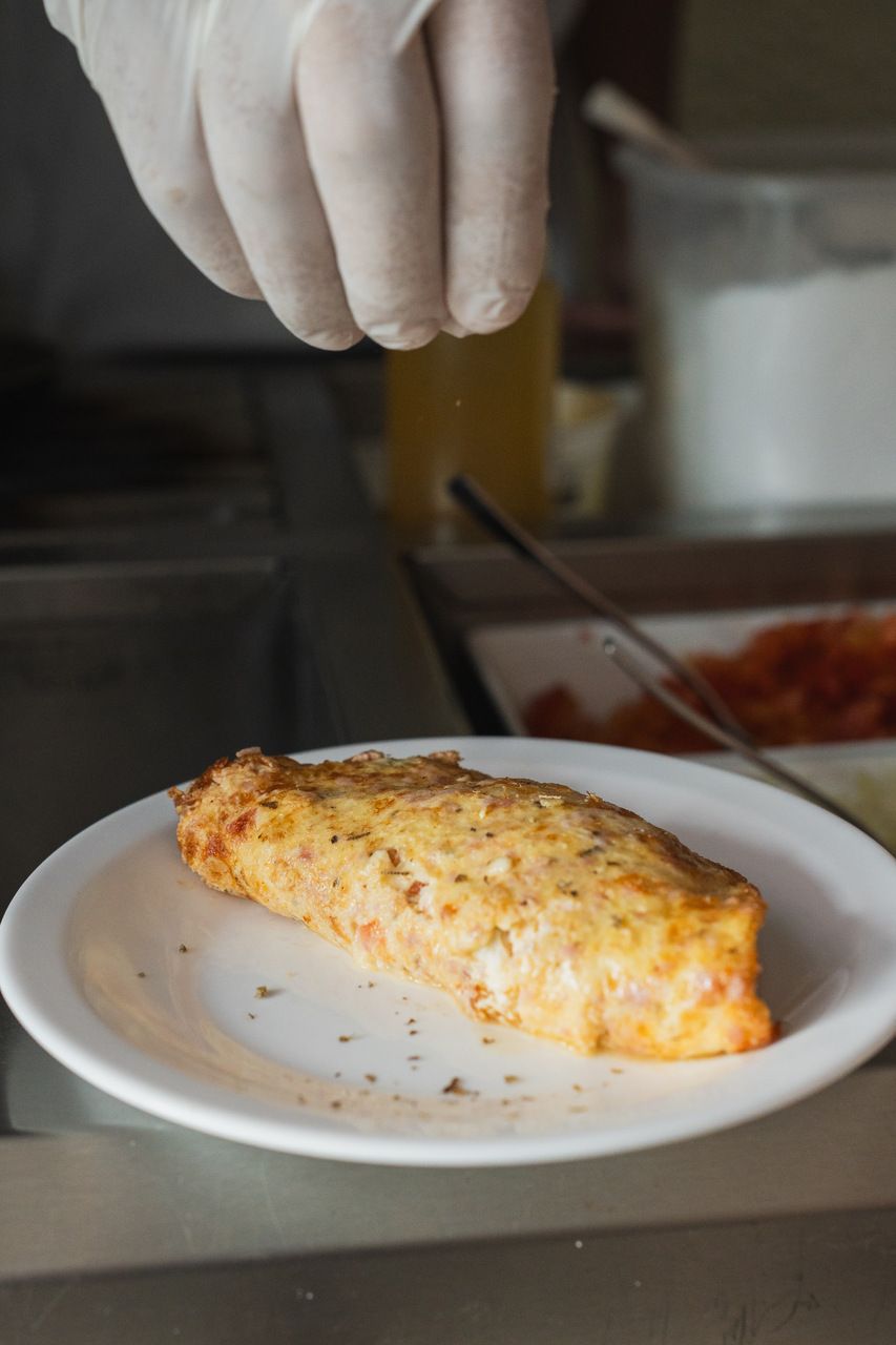Una mano espolvoreando condimentos sobre un plato.