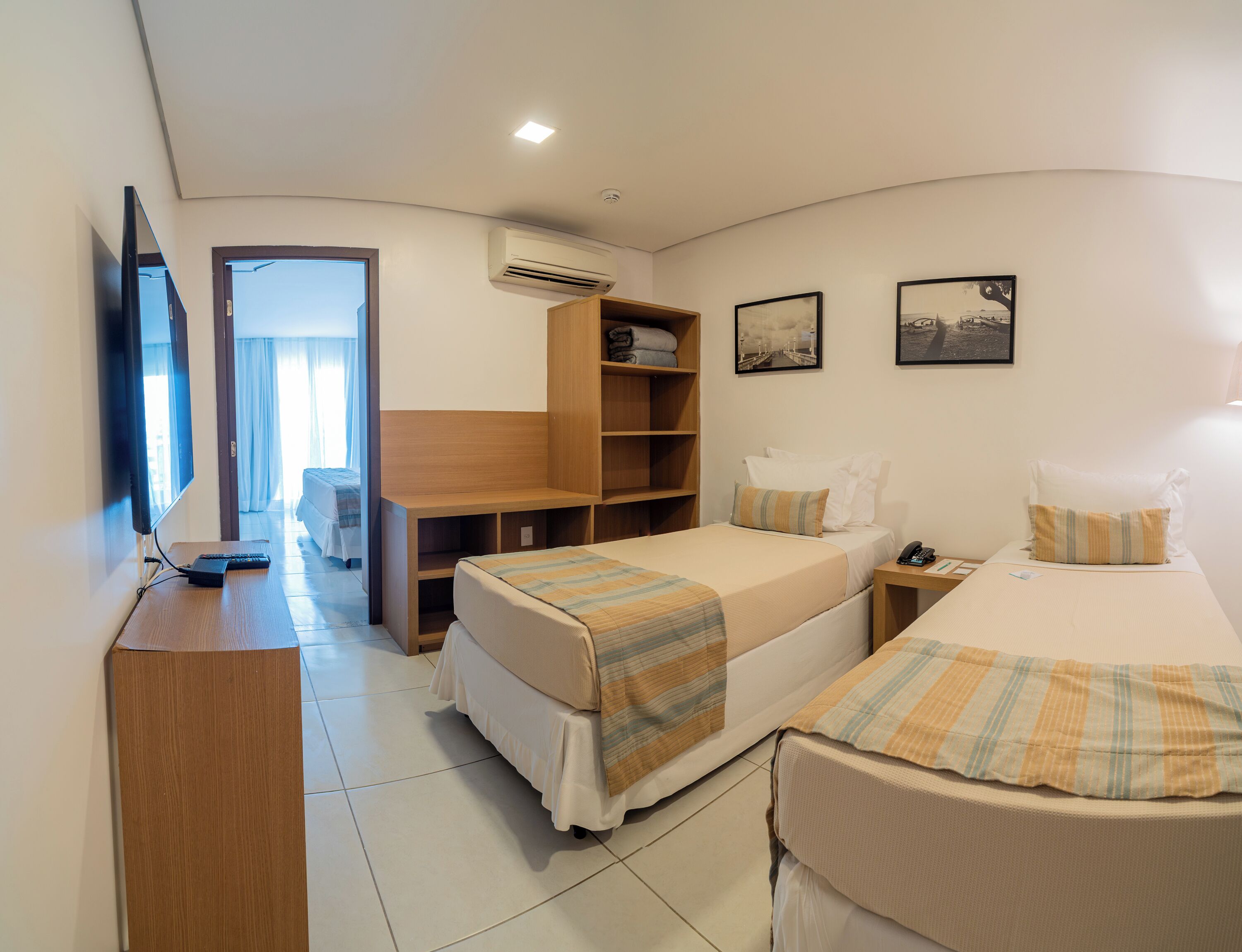Ein Hotelzimmer mit zwei Betten, einem Schreibtisch, einem Fernseher und einem Kleiderschrank.