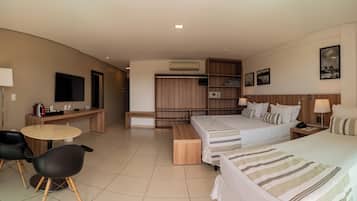 Una habitación de hotel con cama, mesitas de noche, escritorio, sillas, televisor y armario.