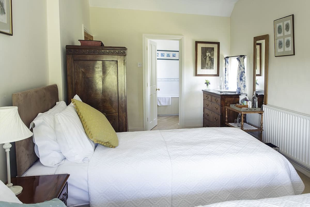 A bedroom with a large bed, a dresser, a mirror, and a door leading to a bathroom.
