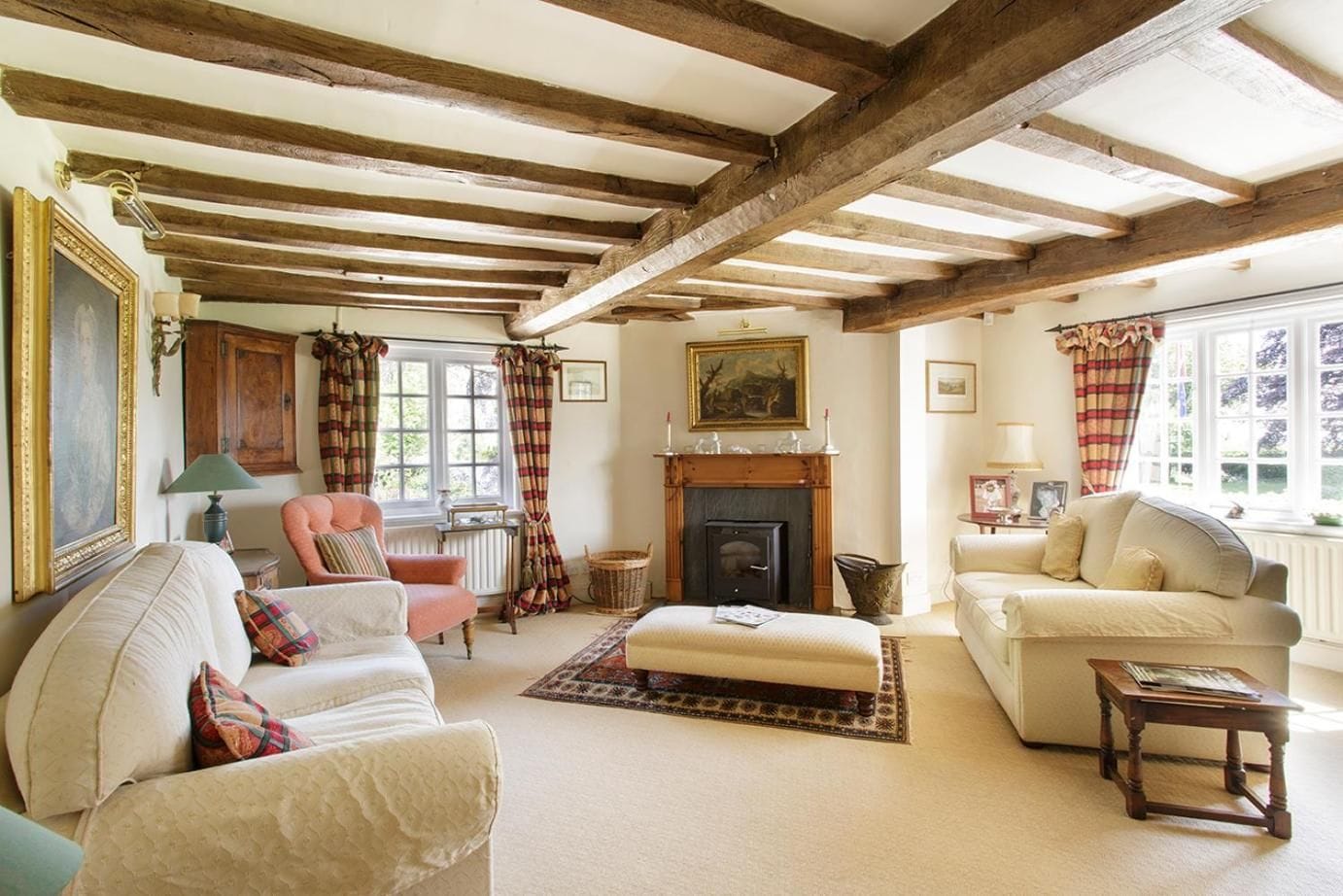 A traditional living room with exposed wooden beams, a fireplace, and classic furniture.