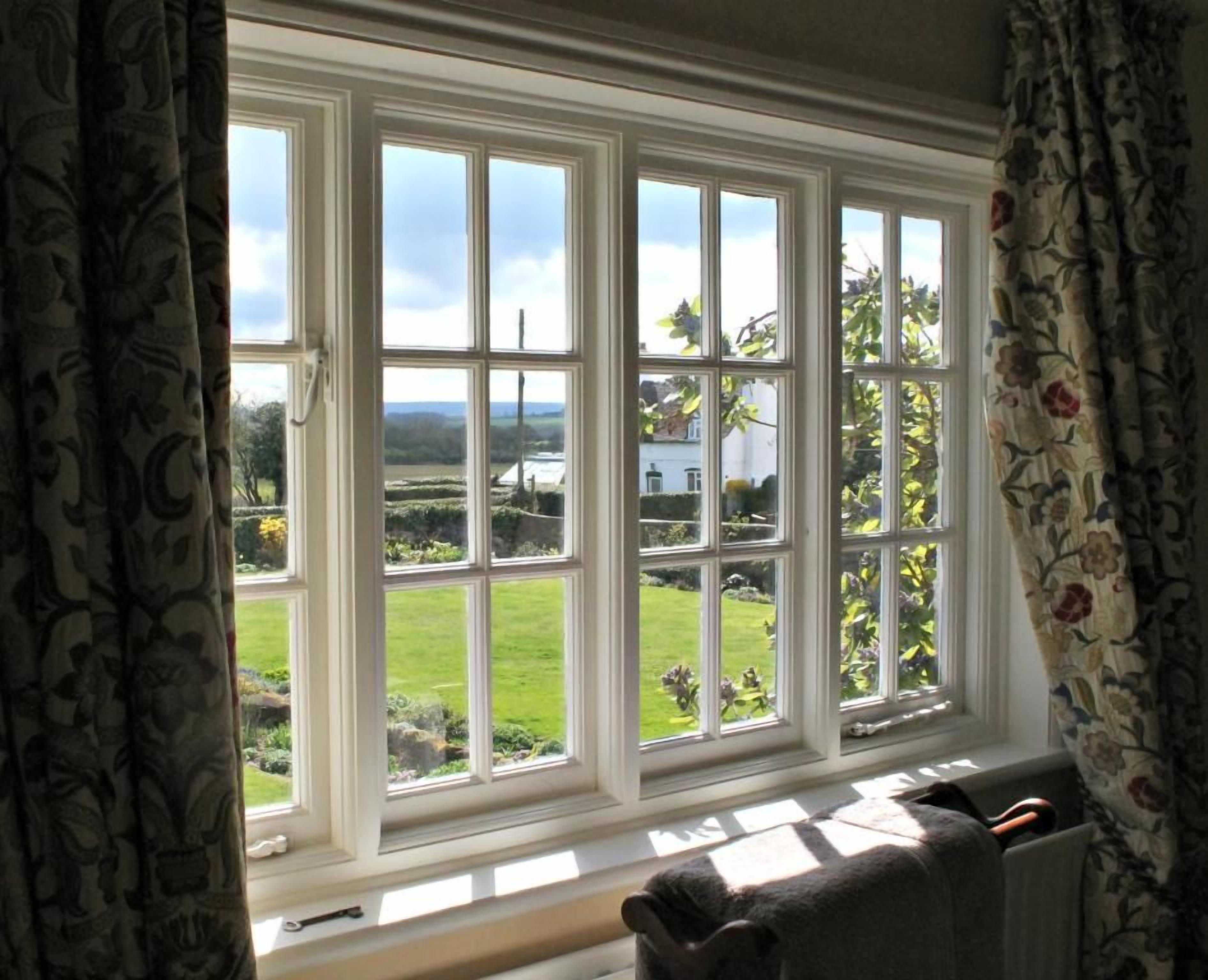 A room with a large window overlooking a garden and a white building.