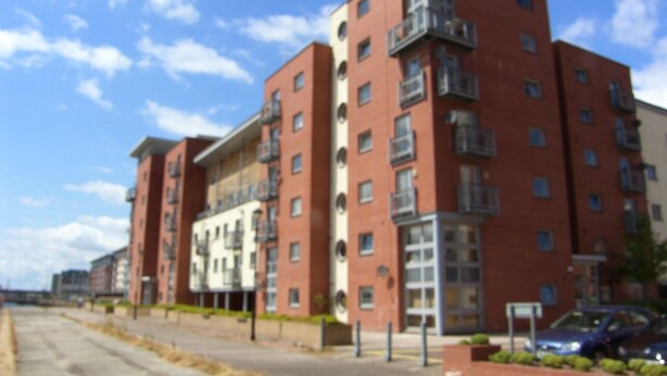 A multi-story residential building with balconies and a parking area in front. - Marine View (Dundee)