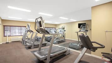Un gimnasio con cintas de correr, elípticas y una bicicleta estática.