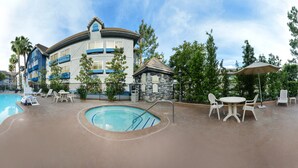 A resort with a large swimming pool, multiple lounge areas, and a stone building with a sign.