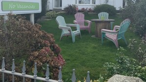 A white building with a sign for Green Apple B&B, featuring outdoor seating and a garden. - Green Apple Bed and Breakfast (St Ives)