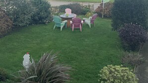 A grassy outdoor area with a table and chairs, a flag, and a view of the sea. - Green Apple Bed and Breakfast (St Ives)