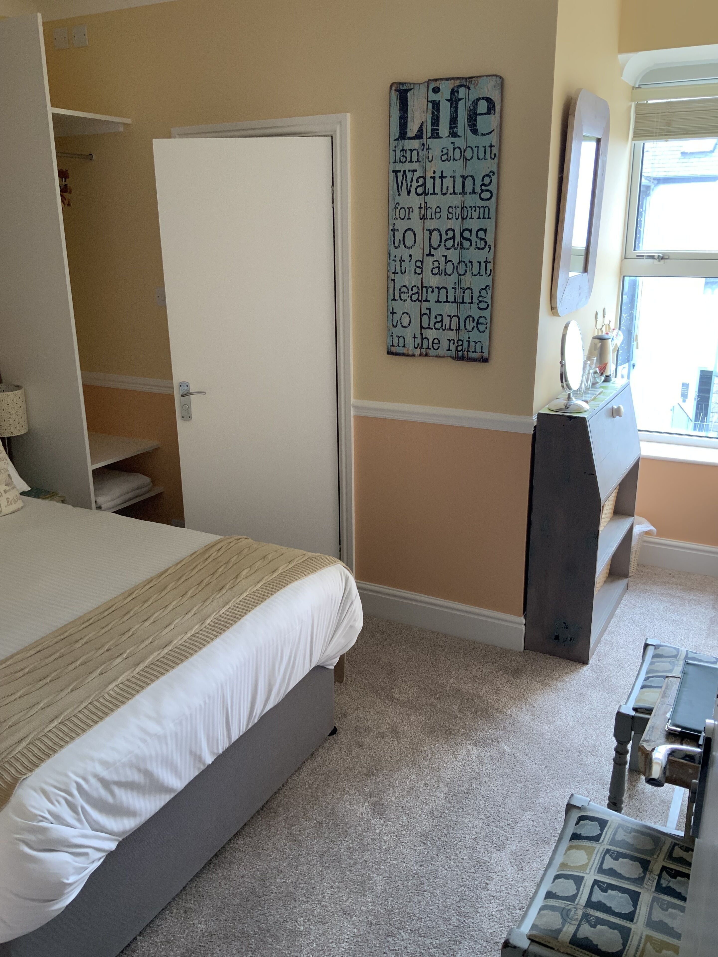 A bedroom with a bed, a dresser, a mirror, and a motivational quote on the wall.