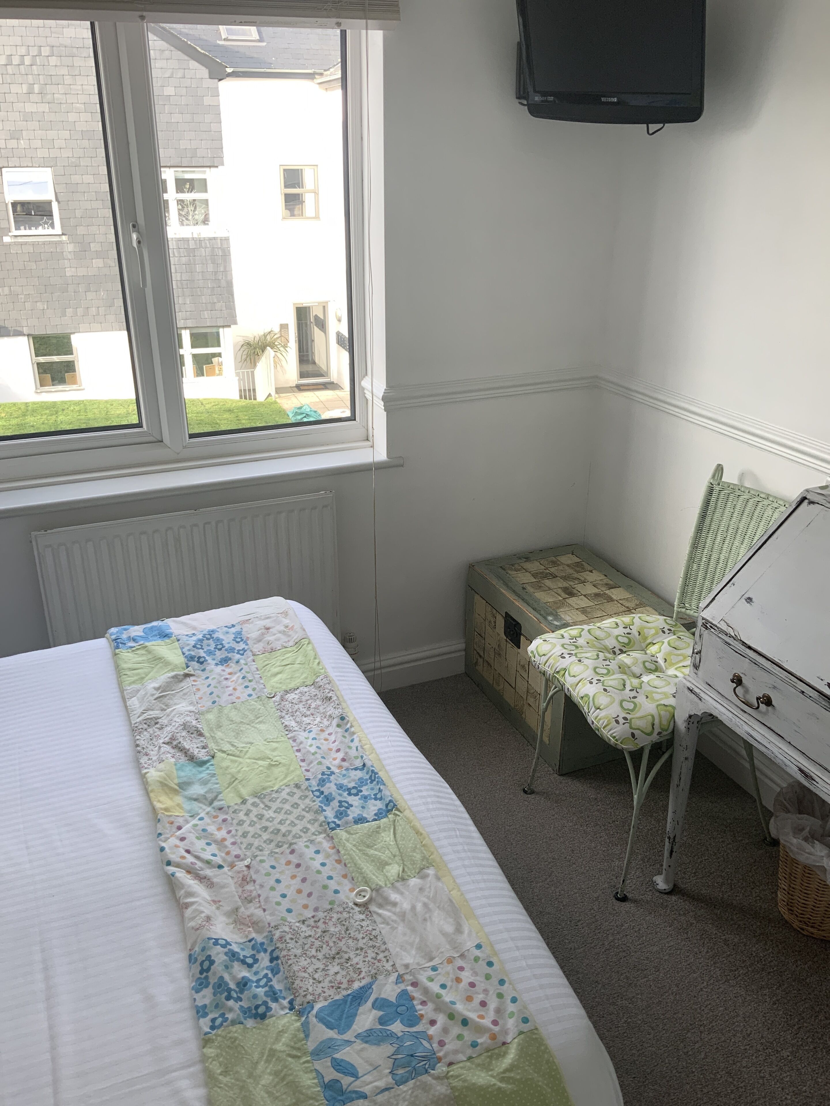 A bedroom with a bed, a window, a desk, and a chair.