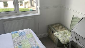 A bedroom with a bed, a window, a desk, and a chair.