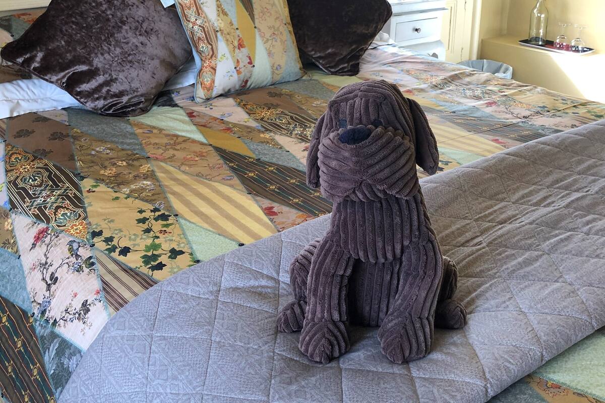 A bed with a quilt, pillows, and a stuffed dog.