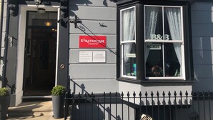 Un edificio con un cartel que dice 'The Strathmore Bed & Breakfast' y un cartel de 'Habitaciones disponibles' en la ventana.