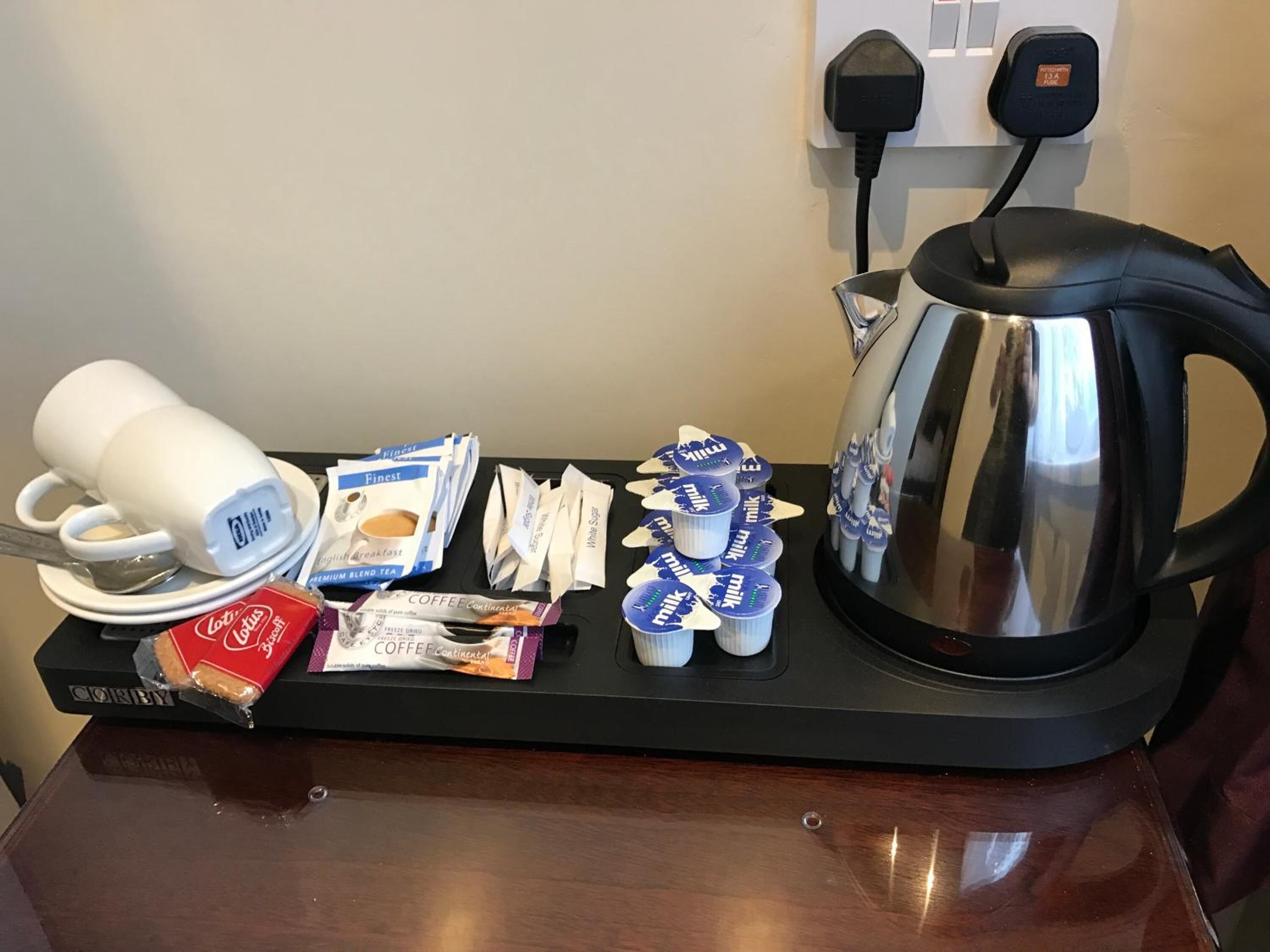 Um espaço para café com cafeteira, xícaras e cápsulas de café em um suporte.