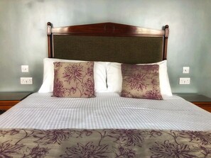 A bed with a wooden headboard, two floral-patterned pillows, and a striped bedspread.