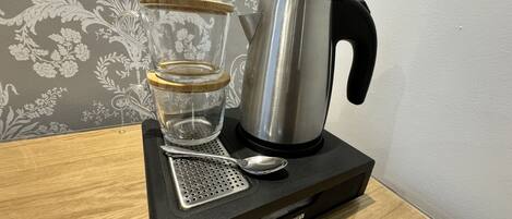 A coffee maker with a glass carafe and a metal pot on a black tray.