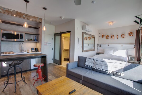 A modern hotel room with a kitchenette, a sofa, a dining table, and a large bed. - Venice V Hotel (Venice)