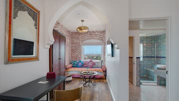 A room with a bed, a desk, and a chair. There is a window with a view of the city.