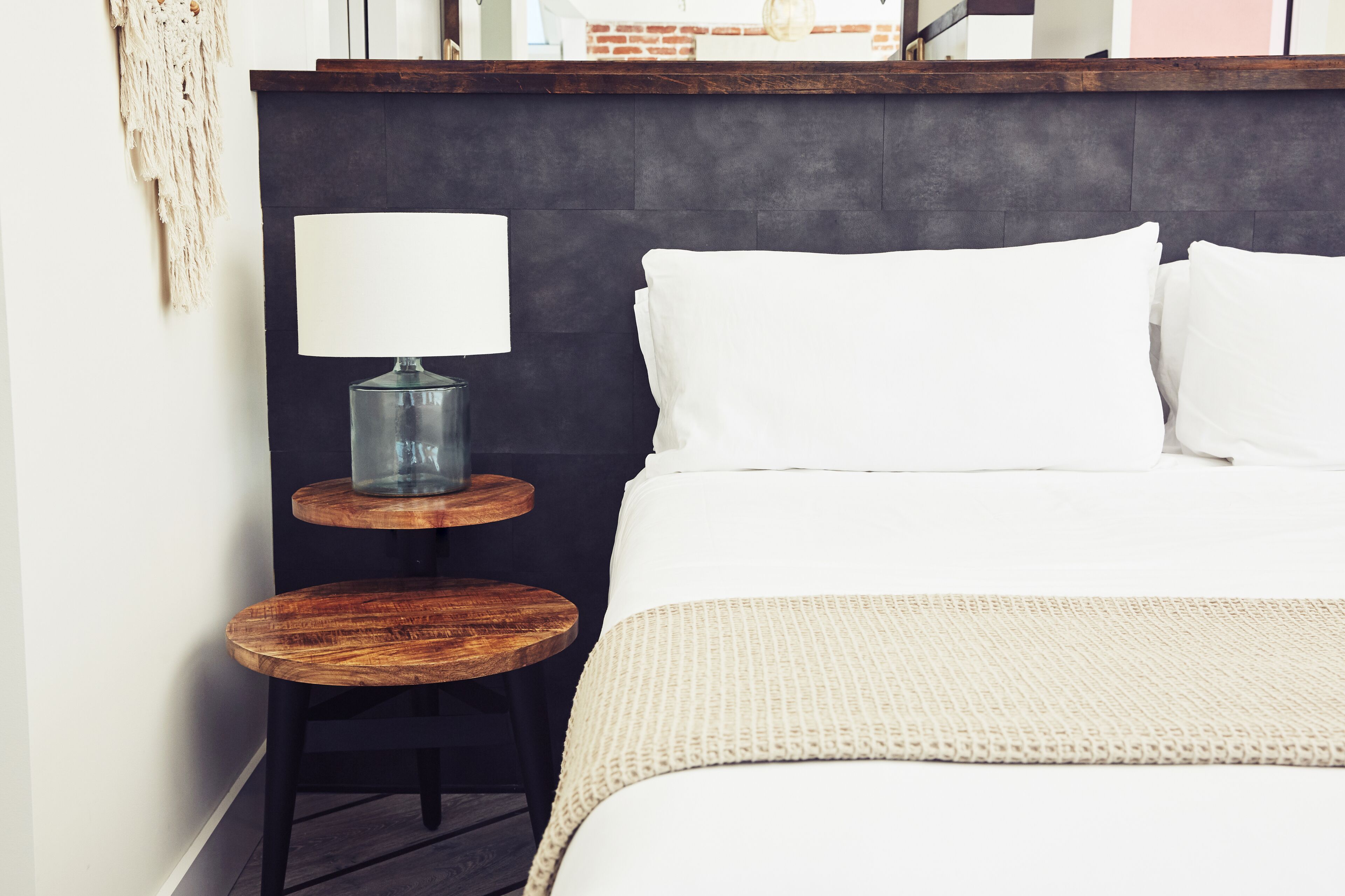 A neatly arranged bedroom with a bed, a bedside table with a lamp, and a small round table.
