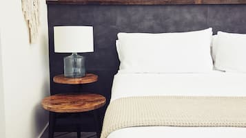 A neatly arranged bedroom with a bed, a bedside table with a lamp, and a small round table.