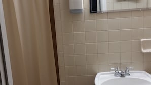 Un bany amb cortina de dutxa, dispensador de sabó, un rentapans i una barra de tovalloles.