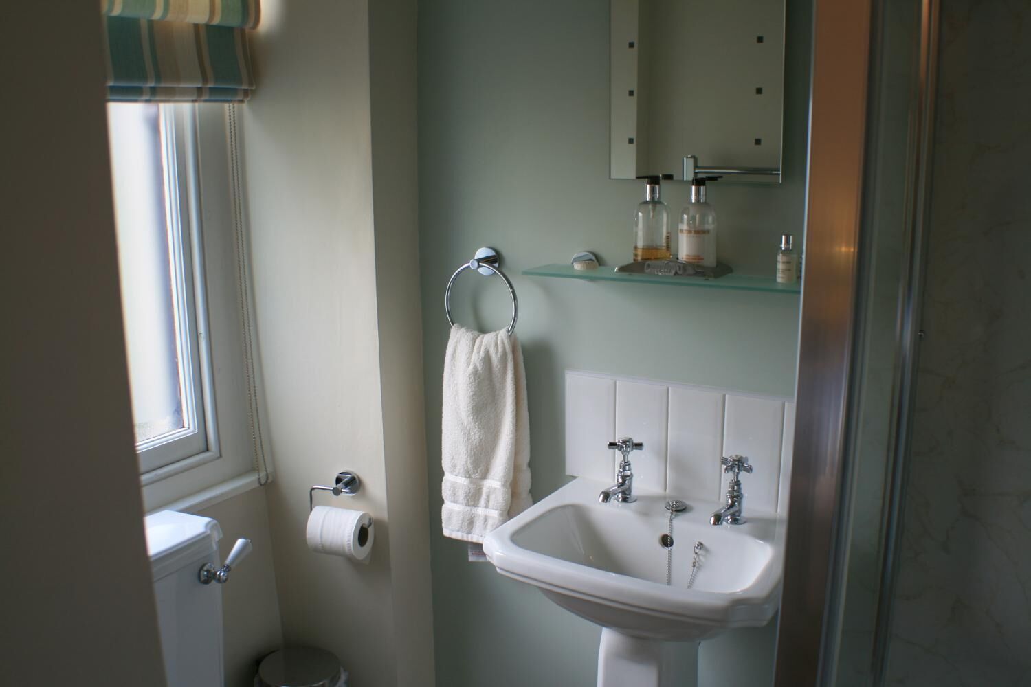 Un baño con inodoro, lavabo y barra para toallas.