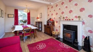 A cozy room with a dining table, chairs, a fireplace, and a red carpet. - Craig Y Glyn (Pwllheli)