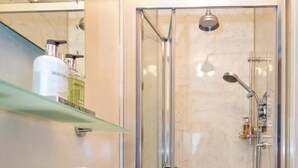 A modern bathroom with a glass-enclosed shower, a white sink, and a shelf with toiletries. - Craig Y Glyn (Pwllheli)