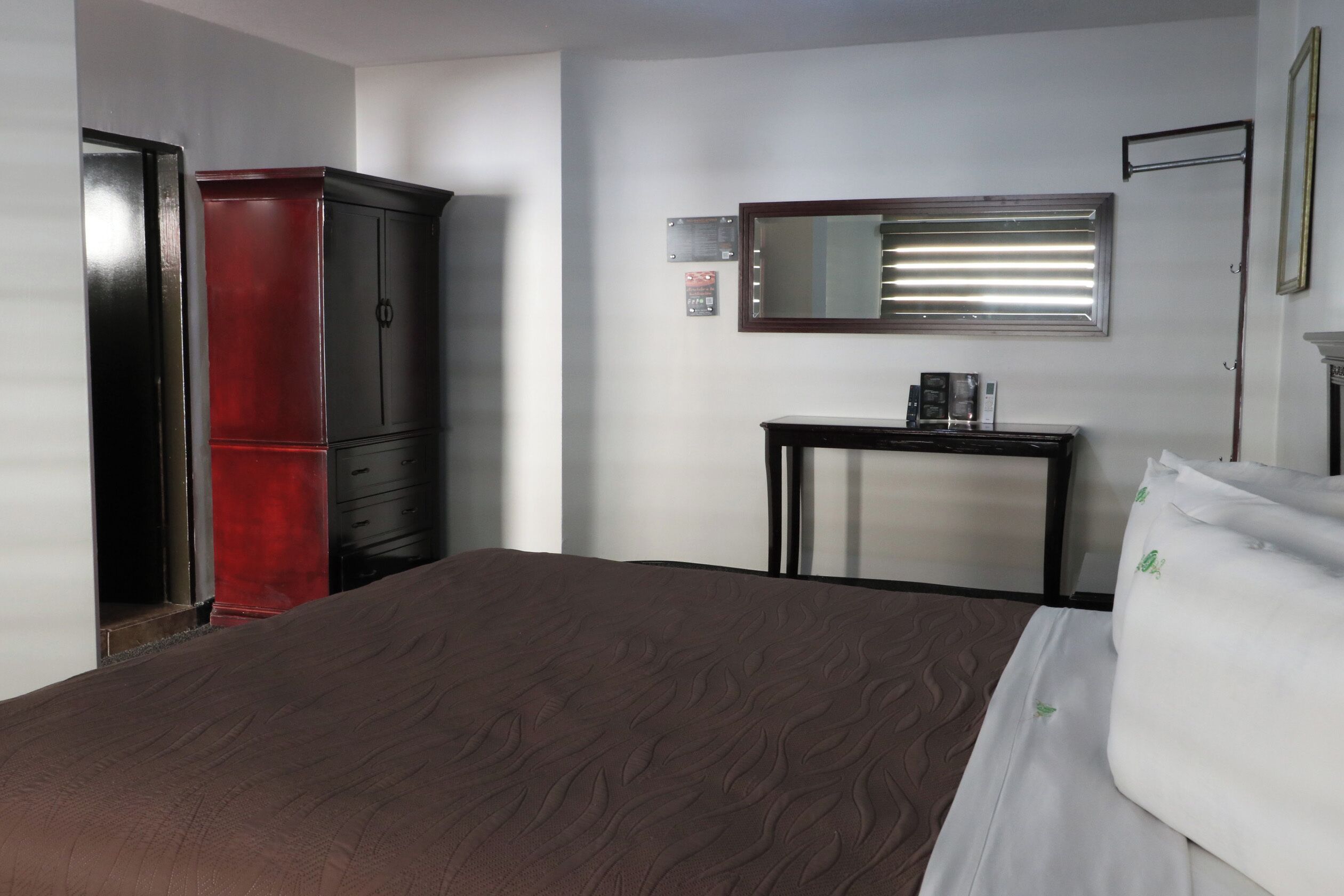 Una camera d'albergo con un letto, un armadio, un comodino e uno specchio.