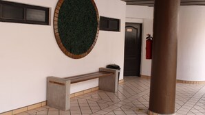 A hallway with a round green wall decoration, a bench, a door, and a fire extinguisher. - Hotel Bugambilias (Ensenada)