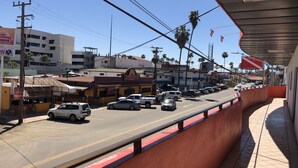 A street view with buildings, parked cars, and a clear sky. - Hotel Bugambilias (Ensenada)