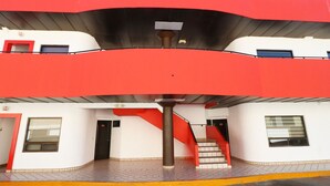 A modern building with a red and white color scheme, featuring a staircase and a central column. - Hotel Bugambilias (Ensenada)