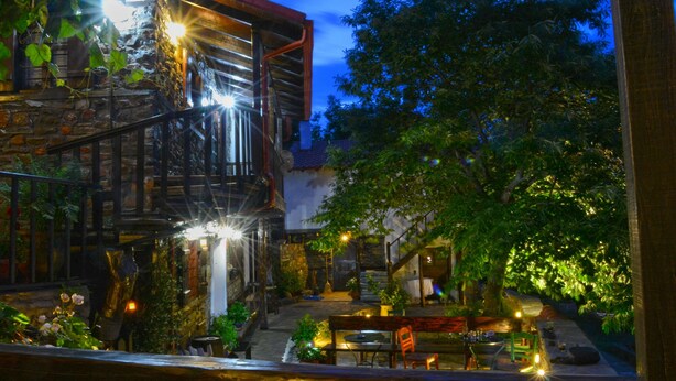 Un patio con un edificio de piedra, bancos de madera y plantas en macetas.