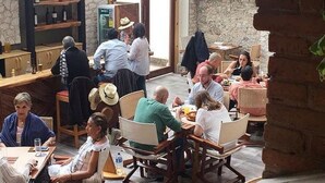 Un amplio espacio al aire libre para comer, con paredes de piedra y ventanas grandes, que cuenta con varias mesas y sillas.