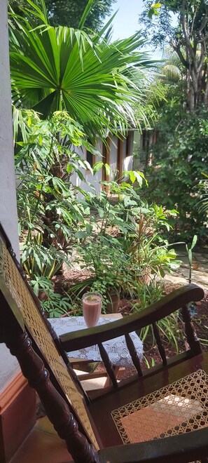 A wooden chair with a woven backrest, a table with a lace tablecloth, and a glass of drink. - Hotel Casa Barcelona (Granada)