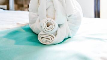 A neatly rolled white towel on a bed in a hotel room.