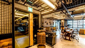 Un intérieur spacieux avec un plafond haut, un éclairage de style industriel et un espace de détente central agrémenté de tables et de chaises.