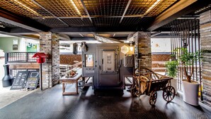 Un café avec un mur en briques, une machine à café et un chariot d’époque.