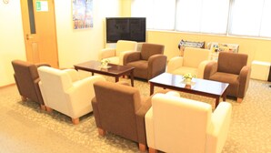 A hotel room with a TV, multiple sofas, a coffee table, and a carpeted floor. - Hotel Ekimae (Hakodate)