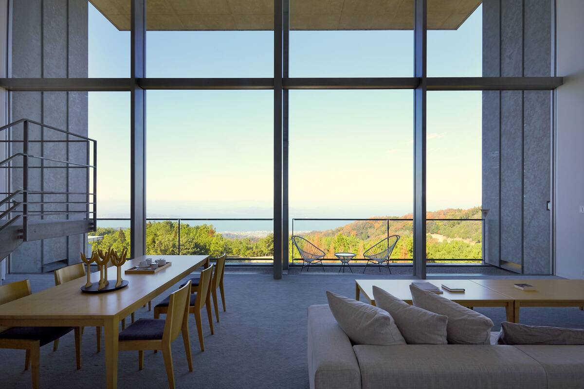 A modern interior with large windows, a dining area, and a sofa.