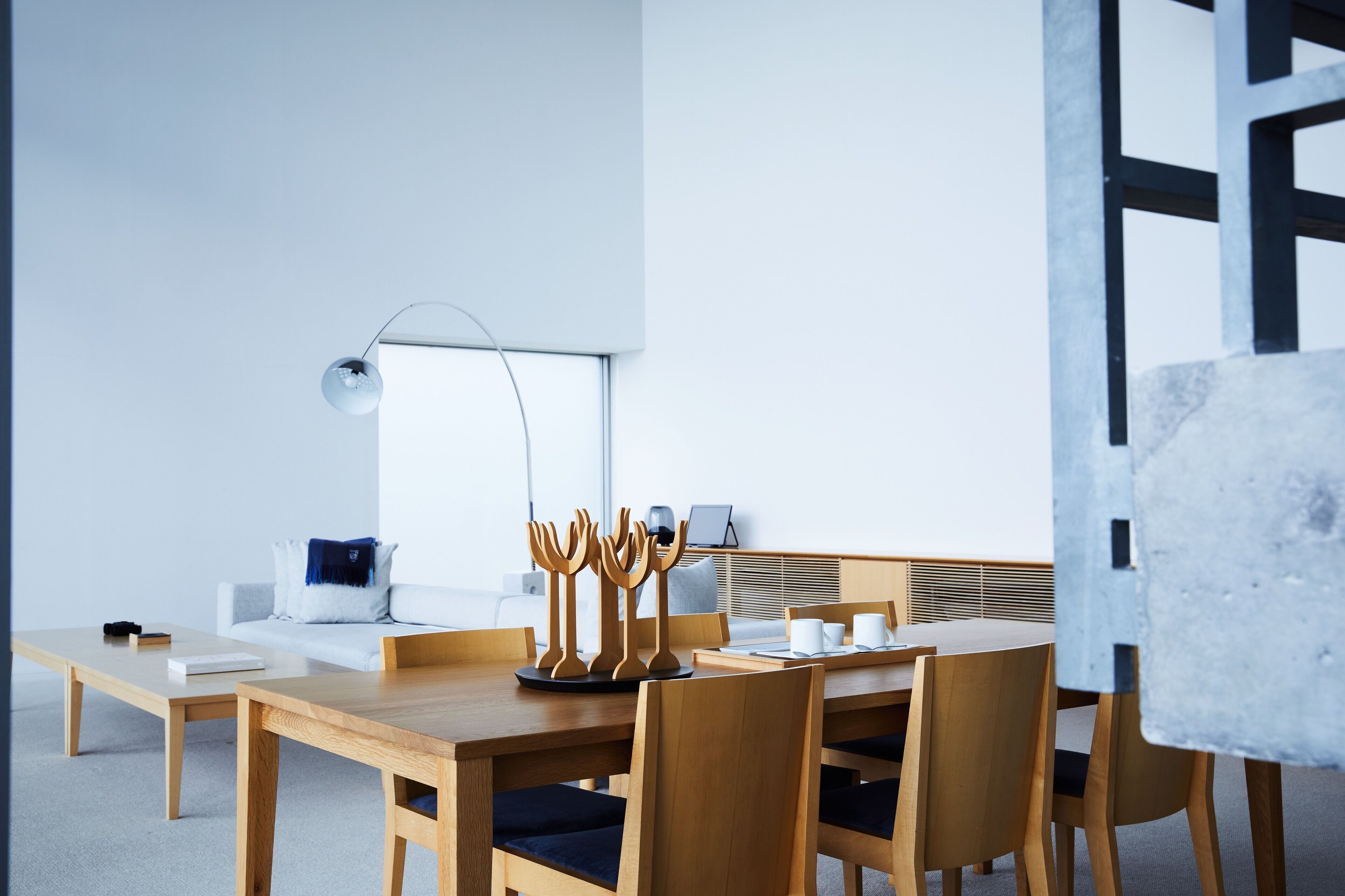 Un comedor moderno y minimalista con una mesa de madera, sillas y un elemento decorativo singular.