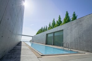 A swimming pool with a concrete wall and a glass door, surrounded by trees. - SETOUCHI RETREAT AONAGI by Onko Chishin (Matsuyama)