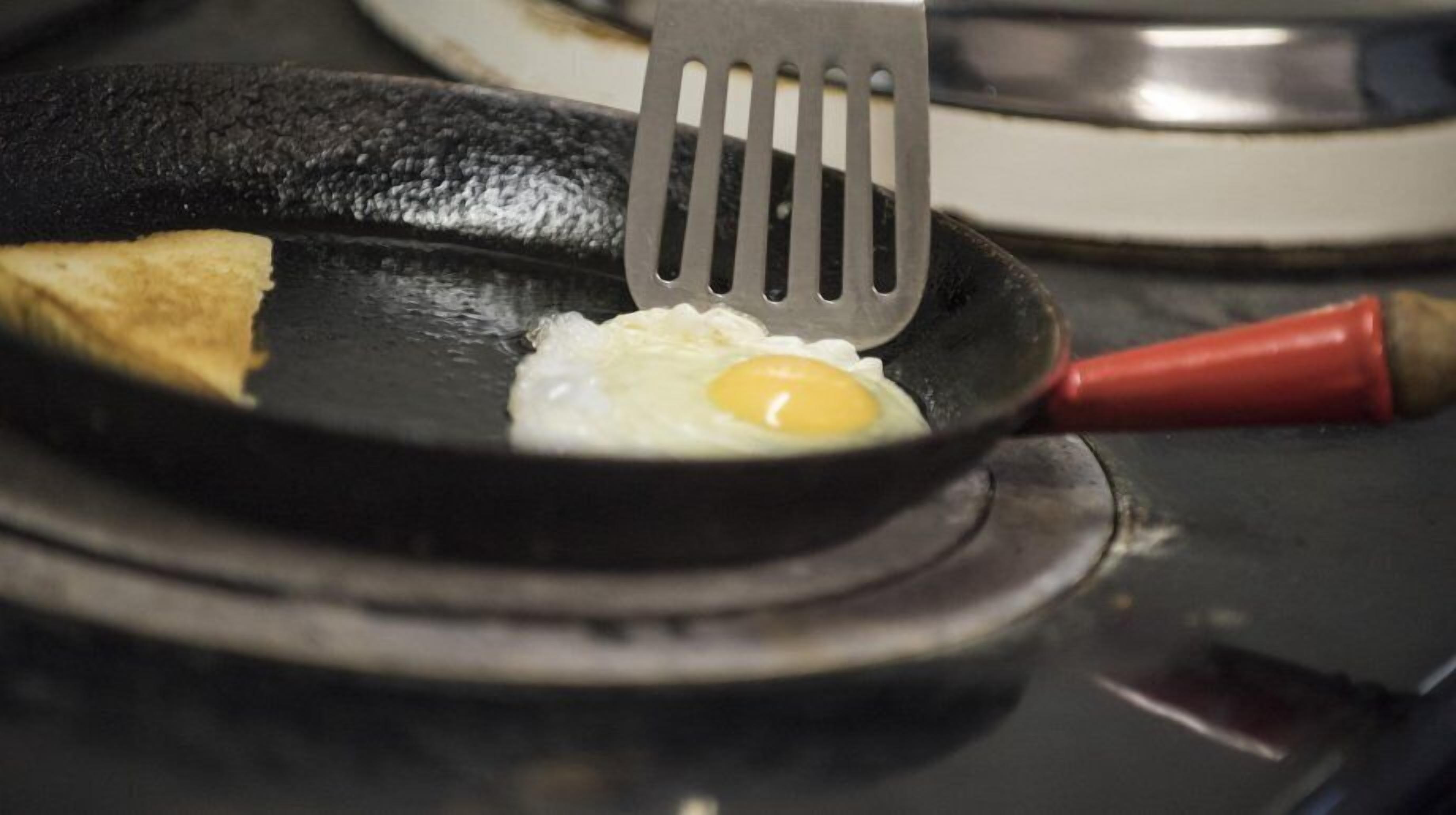 Una sartén con un huevo cocido y una rebanada de tostada sobre una hornilla.