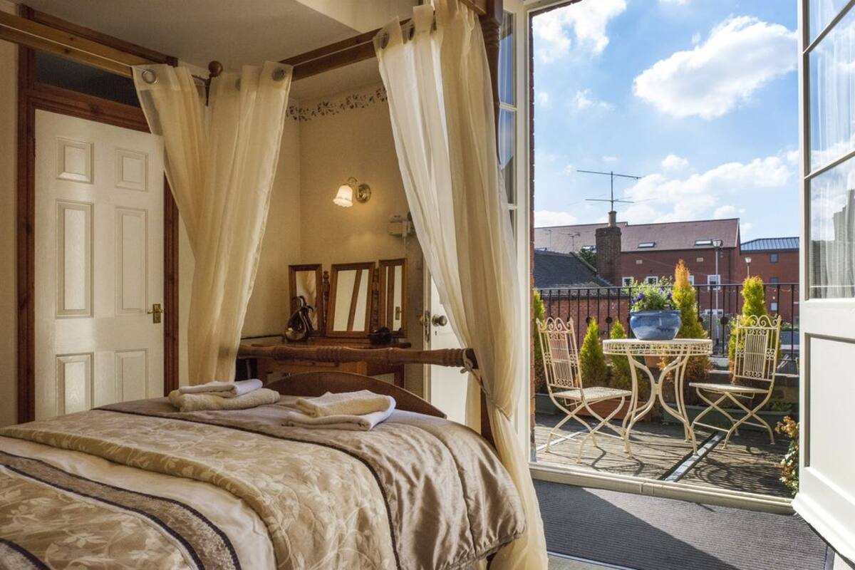 A bedroom with a bed, a dresser, a mirror, and a window with curtains.